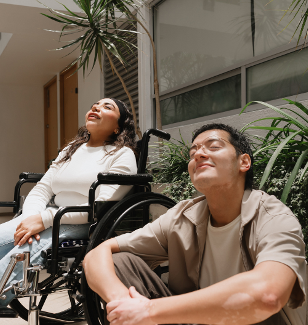 Client in a wheelchair and their support worker basking in the sun.