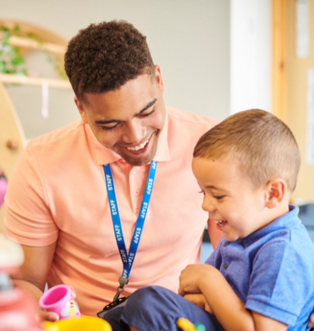 Support Worker and child both laughing and playing with toys.